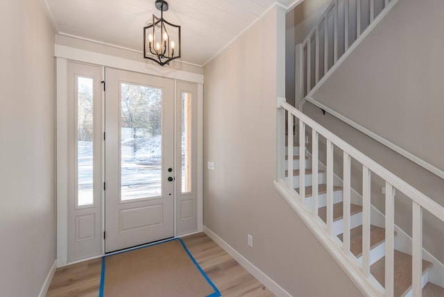 entryway featuring wood finished floors, a chandelier, and baseboards