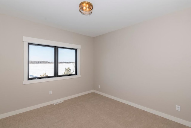 empty room with light carpet, baseboards, and a water view