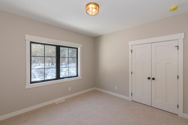 unfurnished bedroom featuring light carpet, baseboards, and a closet