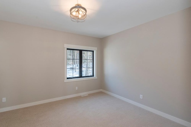 unfurnished room featuring light carpet and baseboards