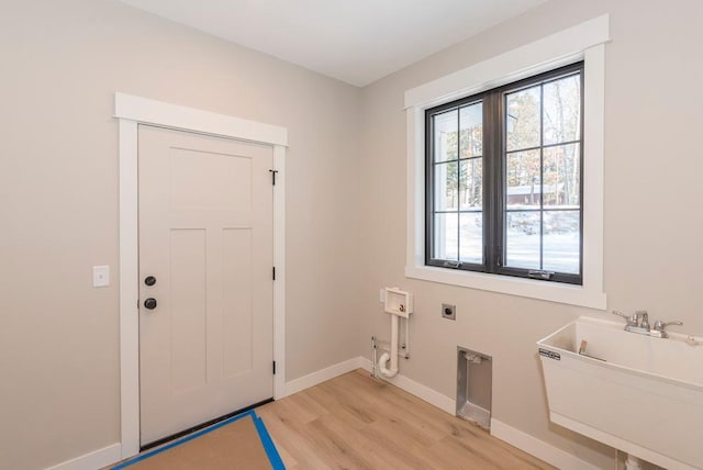 doorway featuring light wood-style floors, baseboards, and a sink
