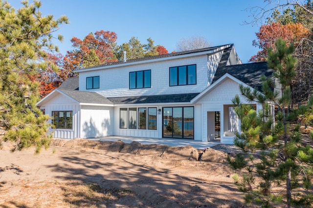 back of house featuring a shingled roof, a patio area, and board and batten siding