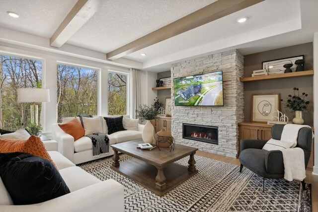 20090 63rd Ave, Corcoran, MN 55340 - living room with beam ceiling, wood finished floors, a fireplace, and a textured ceiling