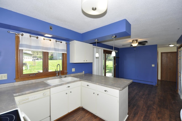 kitchen featuring a sink, dishwasher, a peninsula, dark wood-style flooring, and white cabinets