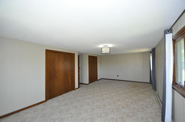 spare room featuring light colored carpet, baseboards, and a baseboard radiator