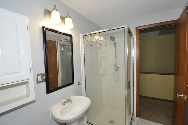 bathroom featuring tile patterned floors, a shower stall, and a sink