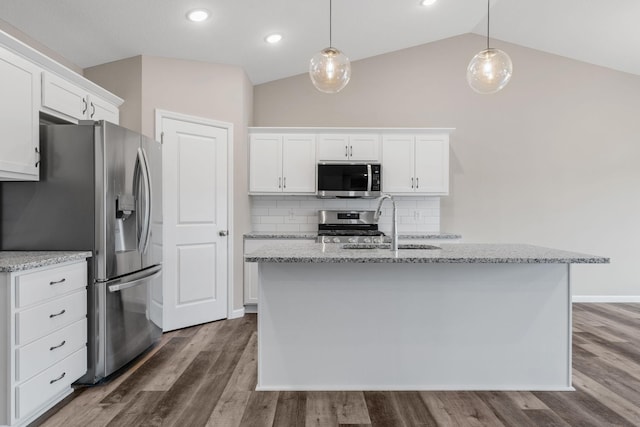kitchen with appliances with stainless steel finishes, a sink, tasteful backsplash, dark wood finished floors, and vaulted ceiling