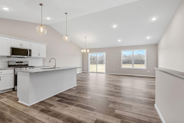 kitchen with stainless steel appliances, a sink, vaulted ceiling, white cabinets, and a chandelier
