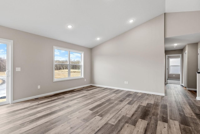 unfurnished living room with vaulted ceiling, plenty of natural light, wood finished floors, baseboards, and recessed lighting