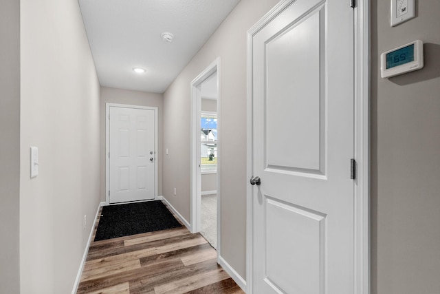 doorway to outside with wood finished floors, baseboards, and recessed lighting