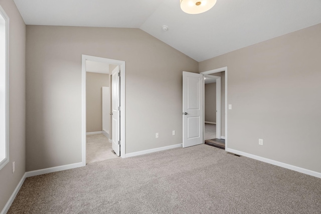 unfurnished bedroom with vaulted ceiling, carpet floors, and baseboards
