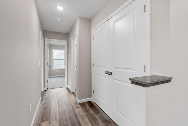 corridor featuring baseboards and wood finished floors