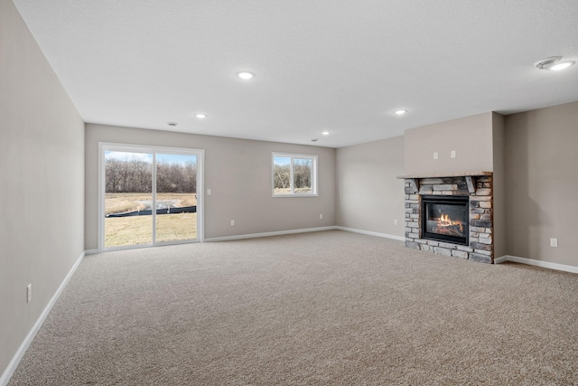 unfurnished living room featuring carpet flooring, baseboards, a fireplace, and recessed lighting