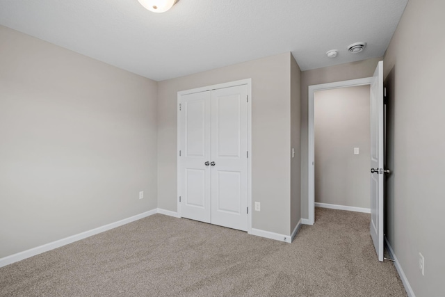 unfurnished bedroom featuring carpet flooring, a closet, and baseboards
