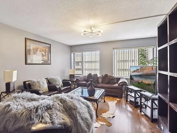 living area featuring plenty of natural light, wood finished floors, a textured ceiling, and a chandelier