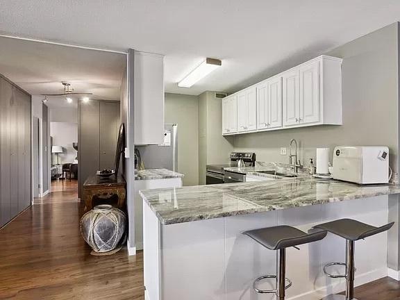 kitchen featuring appliances with stainless steel finishes, dark wood finished floors, a sink, and light stone countertops