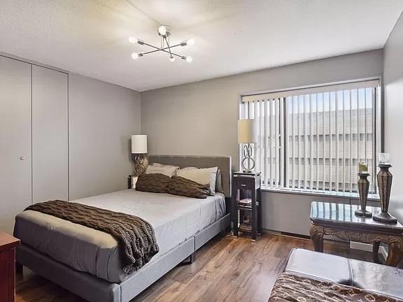 bedroom with a chandelier, wood finished floors, and a closet
