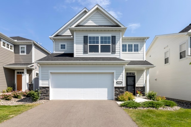 craftsman house with stone siding, asphalt driveway, an attached garage, and a shingled roof