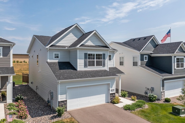view of front of home with an attached garage, asphalt driveway, a shingled roof, and stone siding