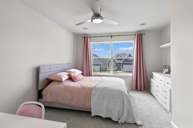 bedroom with light colored carpet, a textured ceiling, and ceiling fan