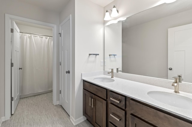 bathroom featuring a sink, double vanity, curtained shower, and baseboards