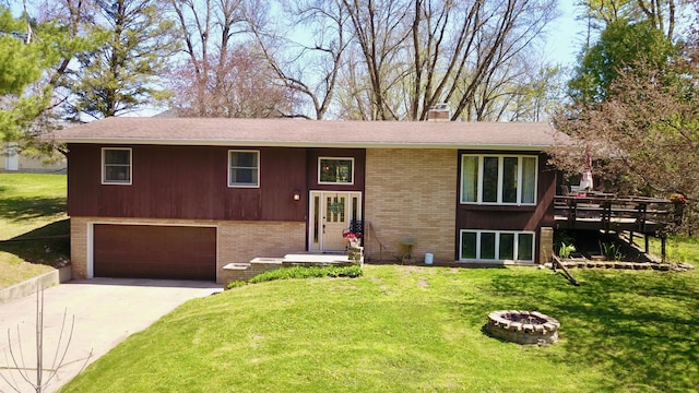 split foyer home featuring a chimney, driveway, brick siding, a garage, and a fire pit