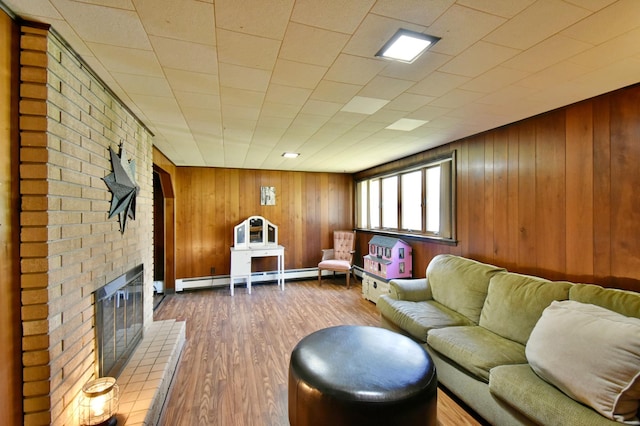 living room with a brick fireplace, baseboard heating, wood walls, and dark wood-type flooring