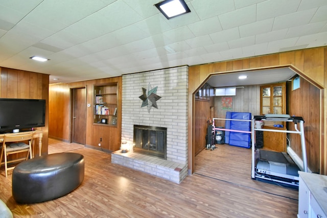 living area featuring a brick fireplace, wood walls, and wood finished floors