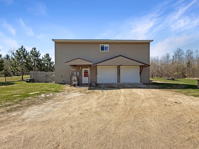 view of front facade with dirt driveway, fence, and an attached garage