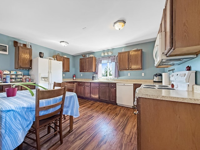 kitchen with white appliances, dark wood finished floors, light countertops, and brown cabinetry