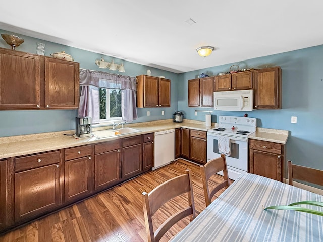 kitchen with white appliances, a sink, wood finished floors, and light countertops