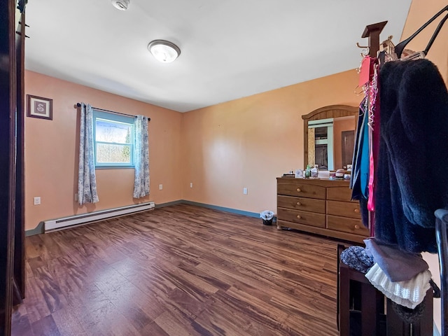 bedroom with a baseboard heating unit, wood finished floors, and baseboards