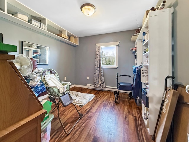 bedroom with dark wood finished floors, baseboards, and a baseboard heating unit
