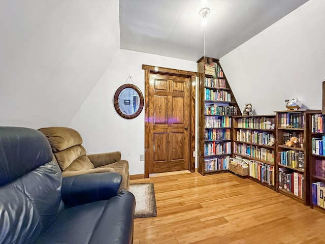 sitting room with light wood-style floors and vaulted ceiling