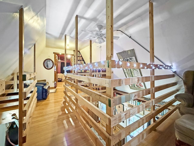 stairway featuring a ceiling fan, wood-type flooring, vaulted ceiling, and baseboards