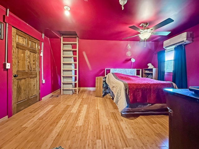 bedroom featuring a wall mounted AC, hardwood / wood-style flooring, and a ceiling fan