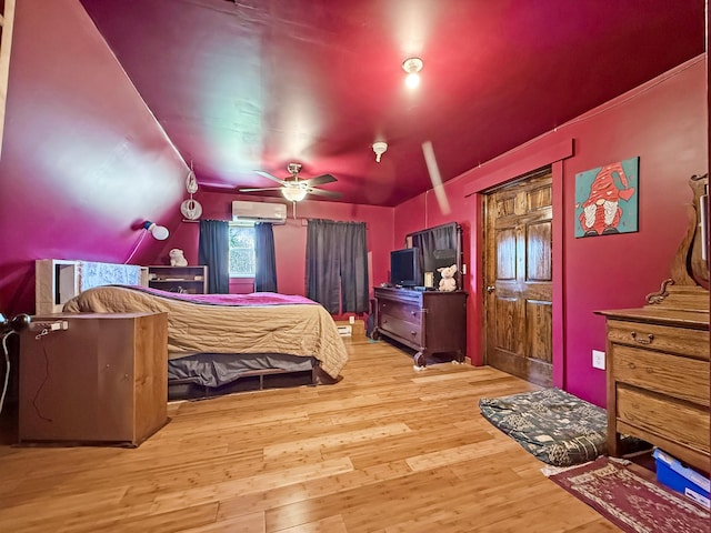 bedroom featuring a wall mounted air conditioner, wood finished floors, and lofted ceiling