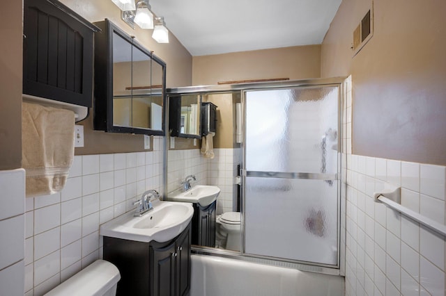 5748 25th Ave S, Minneapolis, MN 55417 - bathroom featuring tile walls, shower / bath combination with glass door, vanity, and a wainscoted wall