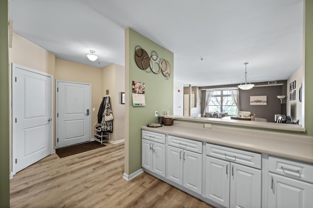 2803 38th St Unit 205, Minneapolis, MN 55406 - kitchen featuring white cabinetry, light countertops, light wood-style floors, pendant lighting, and baseboards