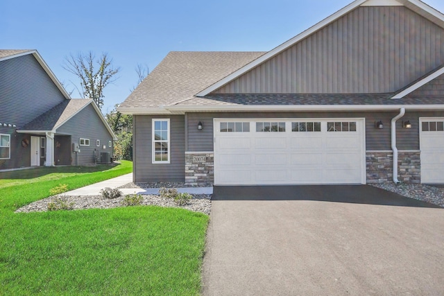 20074 Fitzgerald Trl N, Forest Lake, MN 55025 - view of front of property with stone siding, a front yard, an attached garage, and a shingled roof
