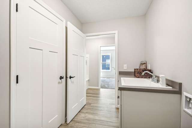 20074 Fitzgerald Trl N, Forest Lake, MN 55025 - hallway featuring a sink, light wood-style flooring, a textured ceiling, and baseboards