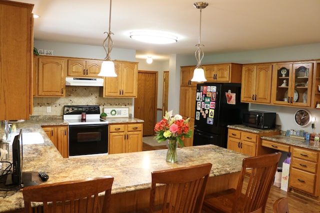 kitchen with black appliances, under cabinet range hood, backsplash, glass insert cabinets, and light stone countertops