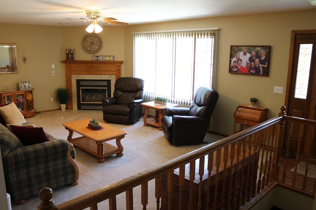 carpeted living room with ceiling fan and a glass covered fireplace