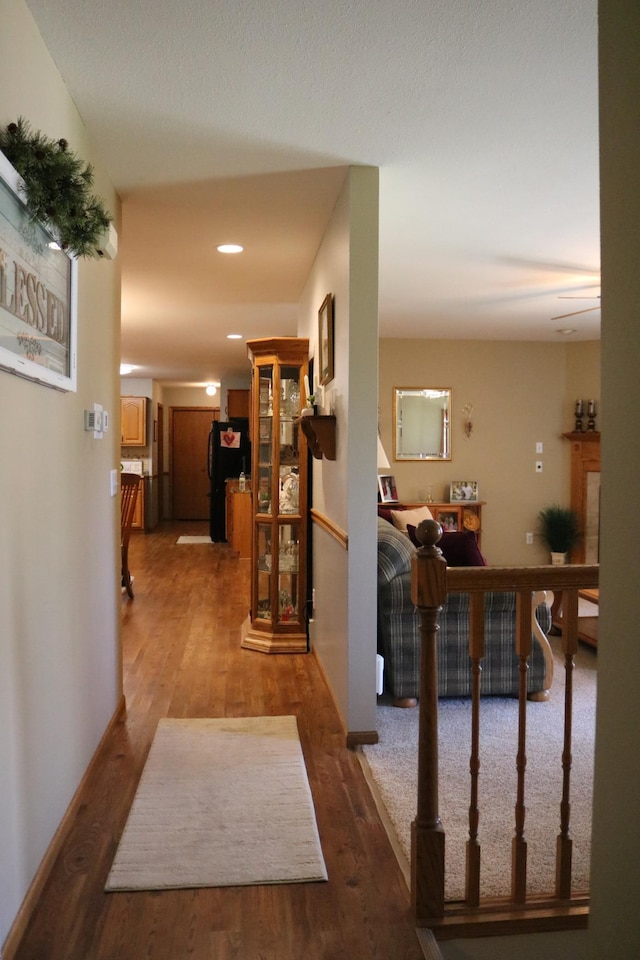 corridor with wood finished floors, recessed lighting, and baseboards