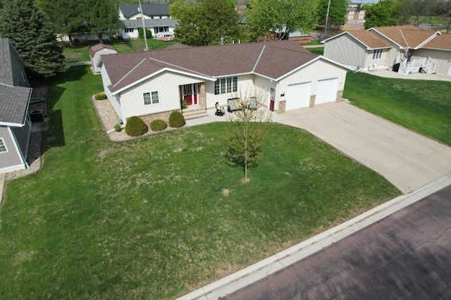 view of front of property featuring an attached garage, concrete driveway, a front lawn, and a residential view