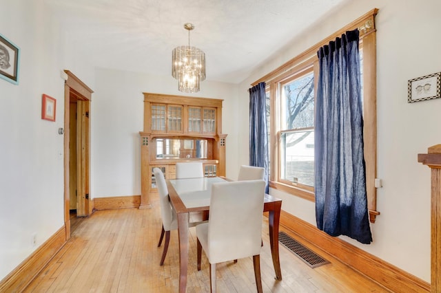dining space with a chandelier, light wood-style flooring, and baseboards