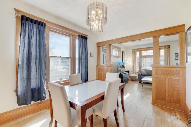 dining space with light wood finished floors, a chandelier, and baseboards