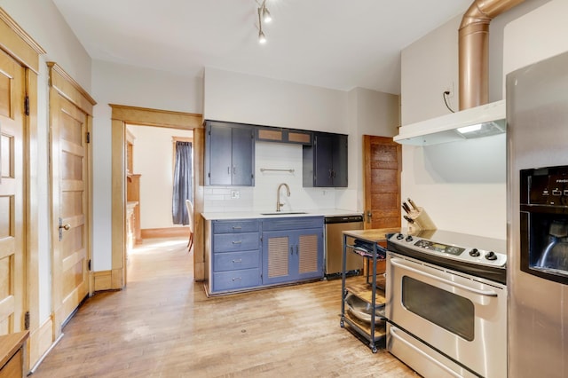 kitchen with appliances with stainless steel finishes, light wood-type flooring, light countertops, a sink, and blue cabinets