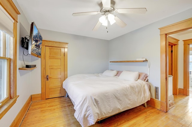 bedroom with light wood-style flooring, baseboards, and ceiling fan