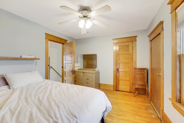 bedroom with light wood-style flooring, baseboards, and ceiling fan